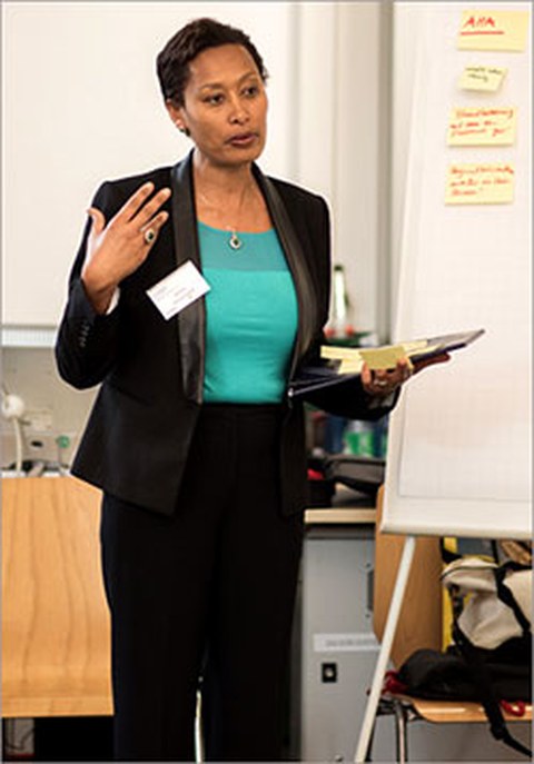 The photo shows Rahel Desalegne standing and holding a presentation.