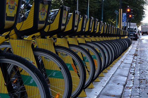 The picture shows a bike sharing docking station with a row of bicycles.