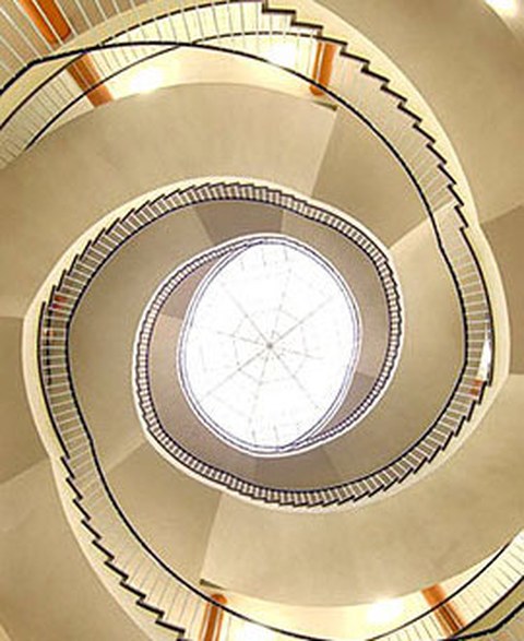 The image shows a spiral staircase, viewed from the center down below looking up toward a skylight.