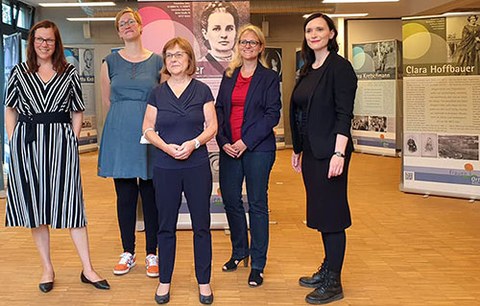 Five women, including Christiane Bonk, stand in front of several exhibition panels in a room.