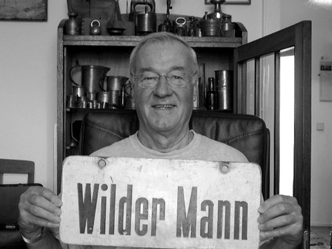 Foto des Autors Ohl mit Brille, der ein Schild mit der Aufschrift "Wilder Mann" vor sich hält