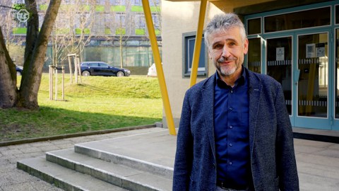 Vice-rector Prof. Kobel looks into the camera. He is standing in front of a building on campus.