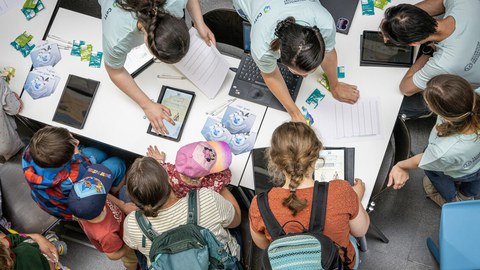 Kinder und Erwachsene arbeiten an Materialien