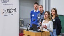 vier Studierende am Rednerpult im Hörsaal