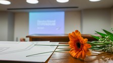 Blume und Urkunde auf Hörsaalbank