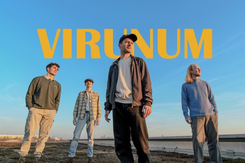 4 Männer die auf einem Flachdach stehend in die Ferne schauen, im Hintergrund der Schriftzug "Virunum"