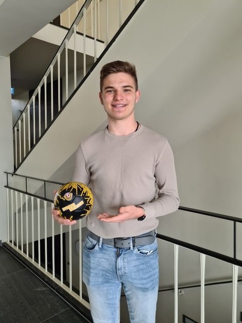 ein junger Mann zeigt einen Ball mit Dynamo-Dresden Logo