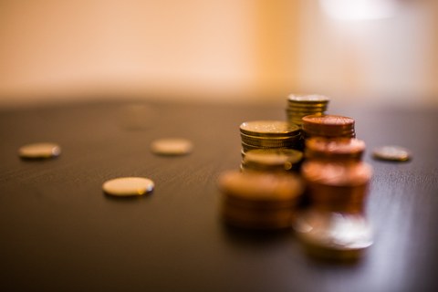 Das Foto zeigt mehrere Stapel an Münzgeld auf einem Tisch. Weiterhin liegen vereinzelte Geldstücke auf dem Tisch.