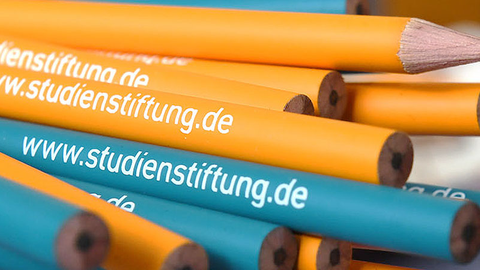 Bleistifte in orange und blau mit dem weißen Schriftzug www.studienstiftung.de