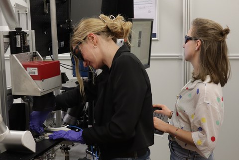 Das Foto zeigt zwei junge Frauen die an einer Anlage arbeiten.