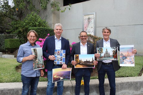 Die 3 Schulleiter des Colegio Aleman Humboldt in Mexiko Stadt und der Studienberater stehen vor der Schule und halten Bilder von Dresden in die Kamera