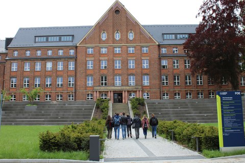 Eine Gruppe Jugendlicher geht auf die große Freitreppe hinter dem Fritz-Foerster-Bau zu. Das Bild zeigt die Gruppe von hinten.
