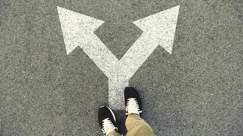 Auf dem Foto sieht man einen Doppelpfeil auf einer asphaltierten Straße. Die Pfeilspitzen zeigen nach rechts und links. Auf dem Pfeil steht eine Person, deren Beine und Füße zu sehen sind.