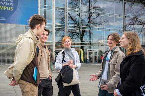 Drei Schüler und zwei Schülerinnen unterhalten sich vor der Glasfront eines Gebäudes