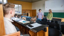 Zwei Schüler:innen stehen in Hörsaal und berichten sitzenden Schüler:innen.