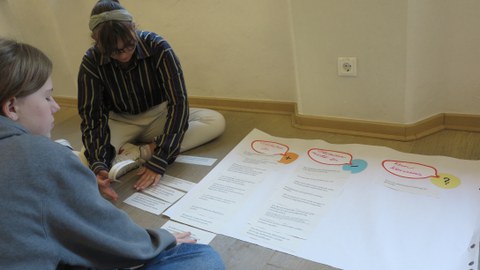 Foto von zwei Schülerinnen, die an einem Plakat basteln.