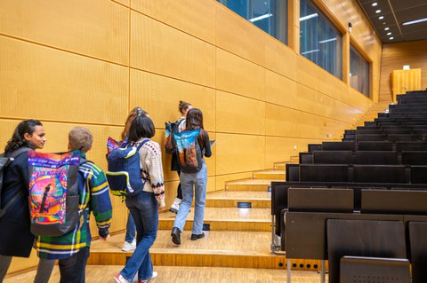 Fotos zeigt sechs Studierende, wie sie in einem Hörsaal auf dem TUD-Campus eine Treppe hochlaufen.