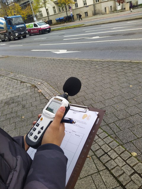 Ein:e Teilnehmende:r verwendet ein Lärmmessungsgerät.
