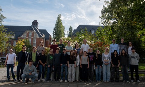 Gruppenfoto der Teilnehmenden. Auf einer Wiese, mit Bäumen im Hintergrund.