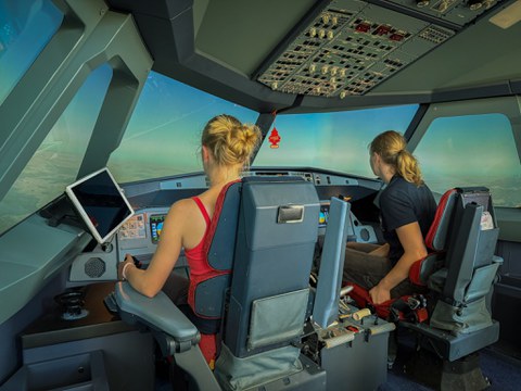 in einem Flugzeugcockpit sitzen zwei junge Frauen. (von hinten zu sehen)