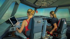 in einem Flugzeugcockpit sitzen zwei junge Frauen. (von hinten zu sehen)
