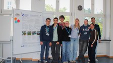 Eine Gruppe Jugendlicher steht mit umgehängten Preisauszeichnung an ihrem Poster.