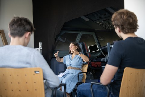 eine Frau erklärt etwas, im Hintergrund der Flugsimulator.