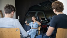 eine Frau erklärt etwas, im Hintergrund der Flugsimulator.