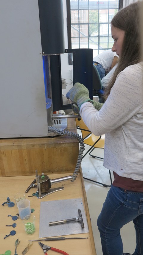 Action-Shot einer Schülerin, die an einem Gerät arbeitet, mit dem Plastikchips hergestellt werden können.