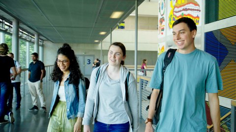 drei Studierende laufen durch das HSZ und unterhalten sich