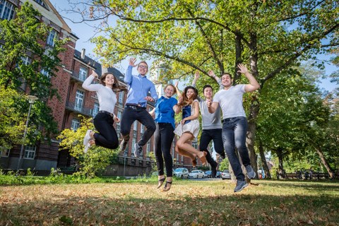 Six students jump into the air in front of the Beyer Building of the TU Dresden
