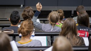 Photo of students in a lecture in a lecture hall from behind. One of them reports in