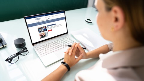 Das Foto zeigt eine Frau die auf einen Laptop schaut. Auf dem Bildschirm ist die Webseite der TU Dresden zu sehen.