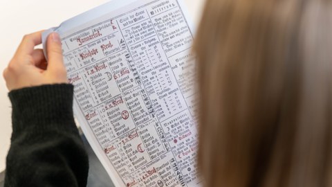 Es ist eine Person zu sehen, die ein Blatt Papier in ihren Händen anschaut.