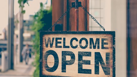 Foto eines Schilds an einer Ladentür; das Schild trägt die Aufschrift "WELCOME OPEN"