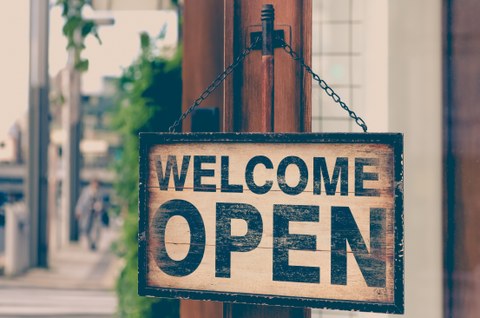 Foto eines Schilds an einer Ladentür; das Schild trägt die Aufschrift "WELCOME OPEN"
