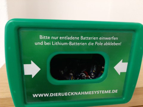 Der Einwurf eines Batteriesammelkästchens mit Beschriftung: "Bitte nur entladene Batterien einwerfen und beiLithium-Ion-Batterien die Pole abkleben!"