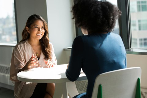 Two women are sitting on a table, talking to each other.