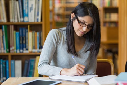 Eine Frau mit langen dunklen Haaren sitz vor einem Bücherregal