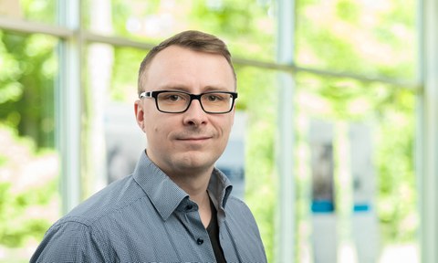 Portraitfoto: freundlich lächelend, Brillenträger, Kurzhaarfrisur