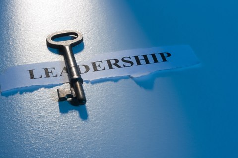 Foto eines Papierschnipsels mit dem Wort "LEADERSHIP" und einem Schlüssel auf weißen Hintergrund