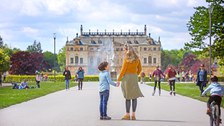 Foto mit Personen und Blick auf das Coselpalais im Großen Garten, eine Mutter steht mit ihrem Sohn hand in Hand davor
