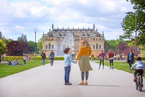 Foto mit Personen und Blick auf das Coselpalais im Großen Garten, eine Mutter steht mit ihrem Sohn hand in Hand davor
