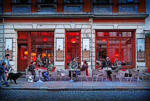 Foto eines Cafes in der neustadt, Gäste sitzen an den Tischen im Außenbereich
