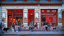 Foto eines Cafes in der neustadt, Gäste sitzen an den Tischen im Außenbereich