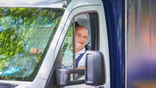 Foto eines TUD-Mitarbeiters, der als Fahrer tätig ist. Er schaut lachend aus seinem Autofenster.enster