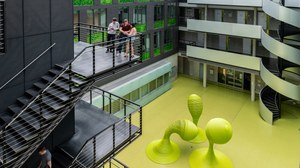 Foto: Studenten auf einer Treppe im Foyer des Andreas-Pfitzmann-Baues mit der Skulptur "Bubbles". 
