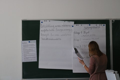 Eine Studentin steht an einer Tafel und beschriftet diese.
