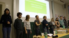 Foto von der Abschlusspräsentation. Eine Gruppe Studierende steht vor einer Leinwand und präsentiert.