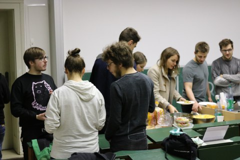 Foto vom GrillING. Viele Studierende stehen in einem Raum und bedienen sich am Buffet.
